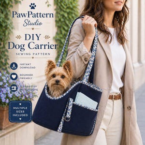 Può includere: Un trasportino per cani blu navy con finiture e cinghie a fantasia floreale. Un cagnolino è all'interno. Il testo dell'immagine dice "DIY Dog Carrier Sewing Pattern". Il trasportino ha una piccola tasca.