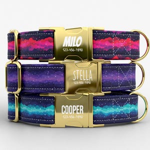 May include: Three personalized dog collars with gold-colored metal buckles. Each collar features a unique space-themed pattern in shades of purple, blue, and pink. The buckles are engraved with a name and phone number: MILO, STELLA, and COOPER.