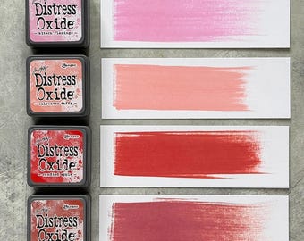 Può includere: Quattro tamponi di inchiostro Distress Oxide in rosa, corallo, rosso e bordeaux, con campioni di colore corrispondenti. I tamponi di inchiostro sono etichettati "kitsch flamingo", "saltwater taffy", "candied apple" e "fired brick". Ideale per progetti di artigianato e mixed media.