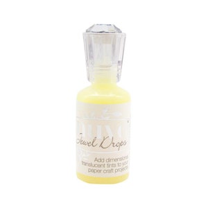 May include: A clear bottle with a diamond-shaped stopper filled with yellow liquid. The bottle is labeled "Nuvo Jewel Drops" and says "Add dimensional translucent tints to your paper craft projects".