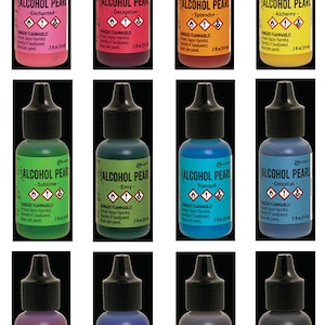 May include: Twelve small bottles of alcohol ink in various colors, each labeled "Alcohol Pearl" with a different color name. The bottles are arranged in three rows of four, with the labels facing the viewer. Each bottle is 5.8 oz (174 ml).