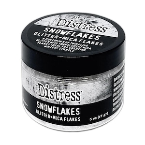 May include: A jar of Distress Snowflakes glitter and mica flakes. The jar has a black lid and a white label with the product name and description. The glitter is a custom mix of twinkling glitter with translucent mica flakes.