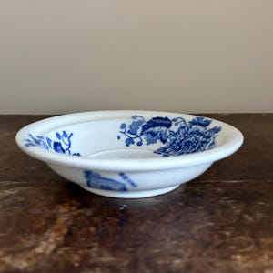 May include: A white ceramic mug with a black handle and the text "But First, Coffee" in a bold, black font. The mug is sitting on a wooden surface. The mug is approximately 4 inches tall.