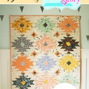 Puede incluir: Una colcha colorida con un patr&oacute;n geom&eacute;trico en tonos naranja, amarillo, verde, azul y rosa. La colcha est&aacute; colgada en una pared y tiene el texto "Wild Blooms" y "Quilt Story" en la parte superior. La colcha est&aacute; disponible en tama&ntilde;os de tiro, doble y queen. El n&uacute;mero de patr&oacute;n de la colcha es #141.