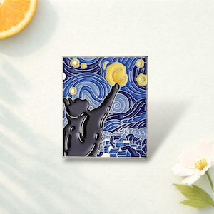 May include: A rectangular enamel pin featuring a black cat silhouette reaching towards a yellow crescent moon. The background displays a swirling blue night sky with stylised clouds and stars, reminiscent of a famous post-impressionist painting.