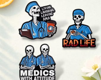 Puede incluir: Conjunto de tres pines de esmalte con figuras de esqueletos con uniformes médicos. Un pin dice "Living, Laughing, Leaving AMA", otro dice "Rad Life", y el tercero "Medics with Attitude". Los pines son azules, blancos y negros.