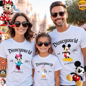 Op de afbeelding: Witte T-shirts met "Disneyworld" in zwart script, met Minnie Mouse, Mickey Mouse en Daisy Duck. Elk shirt heeft "est. 1971" en "FLORIDA" eronder. Een familie draagt de shirts.