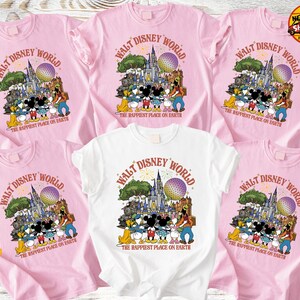 Może przedstawiać: R&oacute;żowe i białe koszulki z kolorowym nadrukiem graficznym z napisem "Walt Disney World" i "The Happiest Place on Earth". Projekt zawiera postacie z kresk&oacute;wek i zamek. Koszulki są z kr&oacute;tkim rękawem.