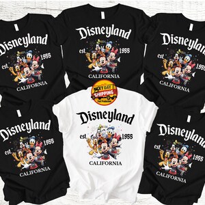May include: Black and white t-shirts featuring the Disneyland logo with Mickey Mouse and friends. The shirts have the text "est. 1955 CALIFORNIA". One shirt is white. The image includes a "Next Day Shipping" sticker.