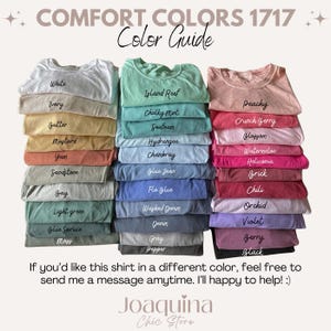 Pu&ograve; includere: Una guida ai colori mostra pile di magliette in varie tonalit&agrave;, tra cui bianco, avorio e senape. La guida presenta anche tonalit&agrave; come scogliera dell'isola, pesca e bacca. Il testo in alto recita "COMFORT COLORS 1717 Color Guide."