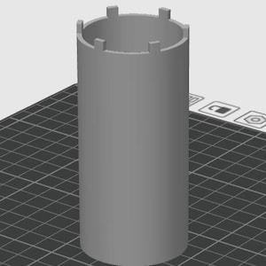 Puede incluir: Una herramienta cilíndrica gris con protuberancias rectangulares en el borde superior. La herramienta se encuentra sobre un fondo de cuadrícula, lo que sugiere un diseño digital o un modelo 3D. El diseño es simple y funcional.