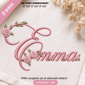 May include: Machine embroidery design of the name Emma in a cursive font, featuring pink thread roses and green leaves. Text includes BX FONT EMBROIDERY 2" 2.5" 3" 3.5" 4" 4.5" and With complete set of alternate letters! 11 FORMAT + BX on a white fabric.