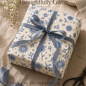 Gift wrapped in floral wrapping paper with dusty blue ribbon in soft natural light setting