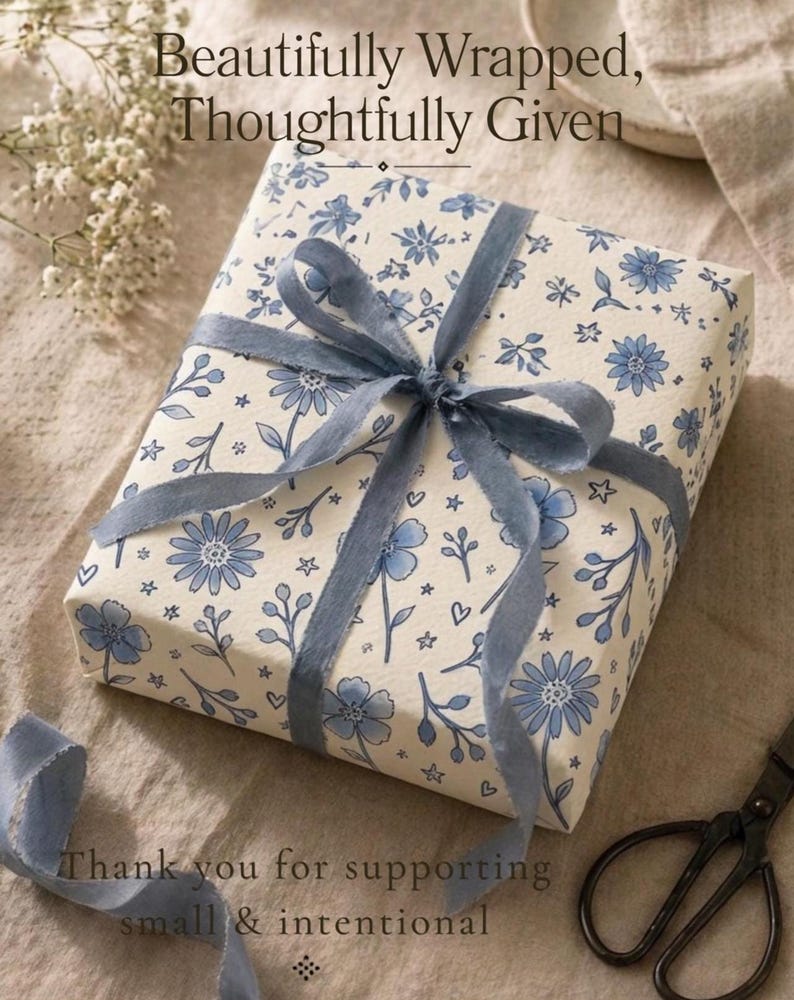 Gift wrapped in floral wrapping paper with dusty blue ribbon in soft natural light setting