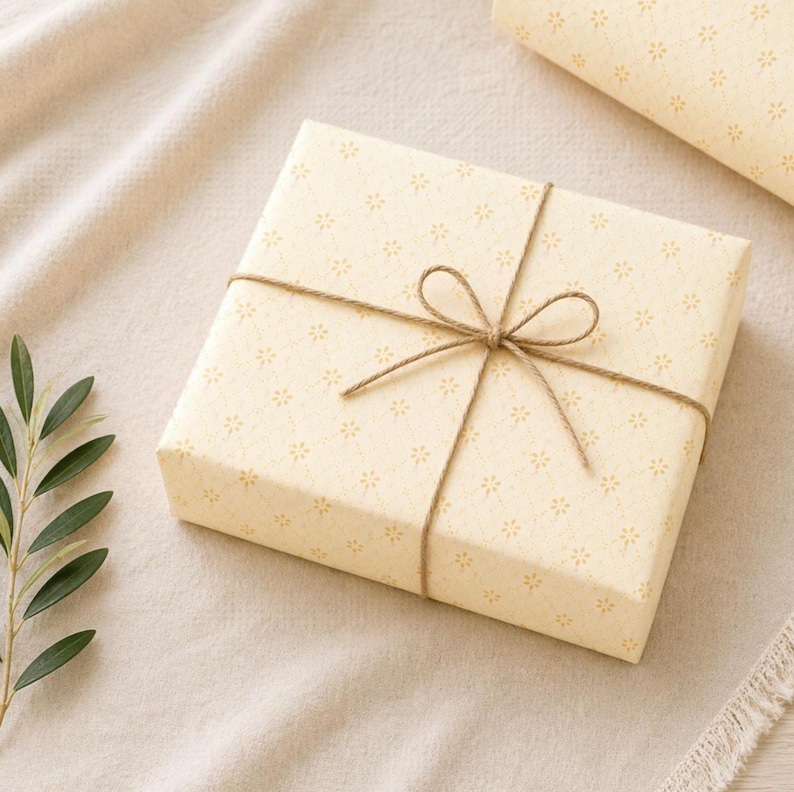 Golden yellow floral wrapping paper wrapped gift styled on a soft linen background with twine bow, warm aesthetic gift wrap for birthdays and gifts for her