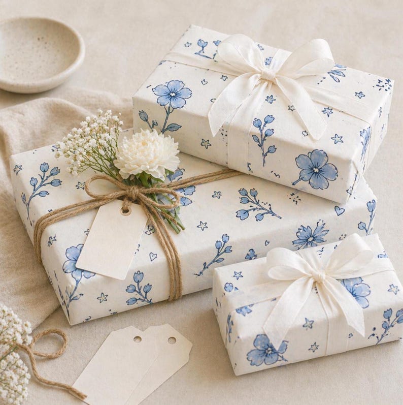 Blue floral wrapping paper on stacked gift boxes with soft ribbon and neutral styling