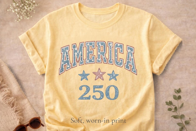 butter yellow patriotic shirt flat lay, vintage america 250 graphic tee on neutral linen background