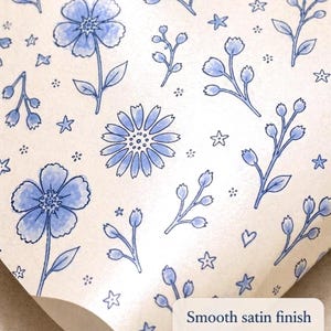 Close-up of floral wrapping paper showing smooth satin finish and hand-drawn blue floral details
