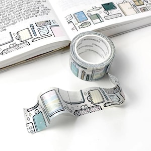 May include: A roll of decorative washi tape with a repeating pattern of notebooks, pens, and other stationery items. The tape is light blue, white, and gray. The text "THE COFFEEMONSTERCO" is printed on the tape roll.