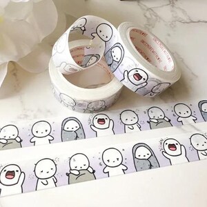 May include: Several rolls of decorative washi tape featuring a repeating pattern of cartoon figures in various poses. The tape is primarily white with light purple and grey accents. The cartoon figures are white with black outlines and facial features. The tape is ideal for scrapbooking and crafts.