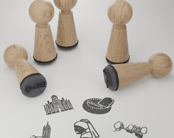 May include: Set of six wooden rubber stamps with black ink pads. The stamps feature various designs, including buildings, a woman's face, and text. The stamps are ideal for crafting and scrapbooking.