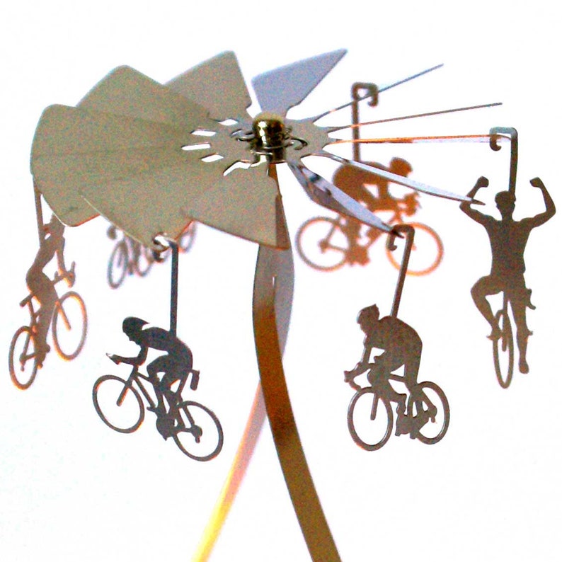 May include: A silver metal mobile with five silhouettes of cyclists riding bicycles. The mobile is suspended from a silver metal base.