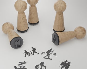 Pode incluir: Cinco carimbos de madeira com almofadas de tinta preta. Os carimbos apresentam vários desenhos de pessoas fazendo caminhadas e acampamentos. Os desenhos incluem uma família de três, uma pessoa com uma mochila, uma pessoa com um bastão de caminhada e uma pessoa com um mapa.