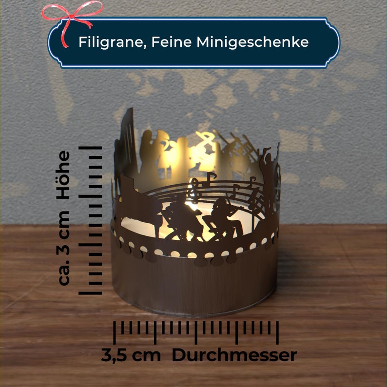 Puede incluir: Un portavelas de metal con una silueta de una banda tocando m&uacute;sica. El portavelas tiene un di&aacute;metro de 3,5 cm y una altura de 3 cm.