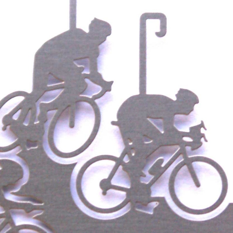May include: A silver metal ornament featuring a silhouette of three cyclists riding bicycles. The ornament has a hook for hanging.