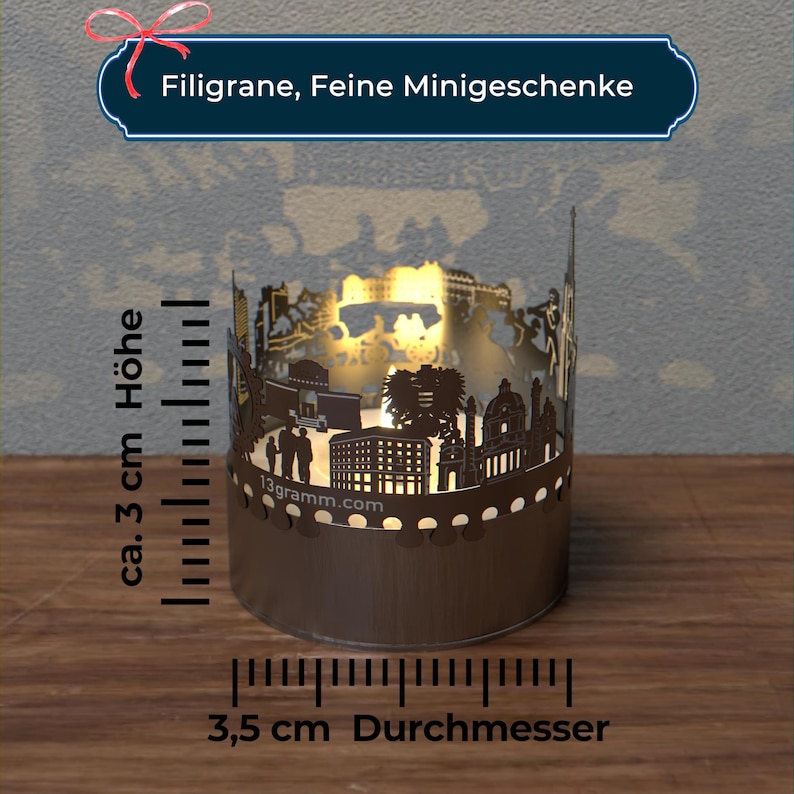 May include: A brown metal candle holder with a cut-out design of a city skyline. The candle holder is 3.5 inches in diameter and 3 inches tall. The text "Filigran, Feine Minigeschenke" is at the top of the image.