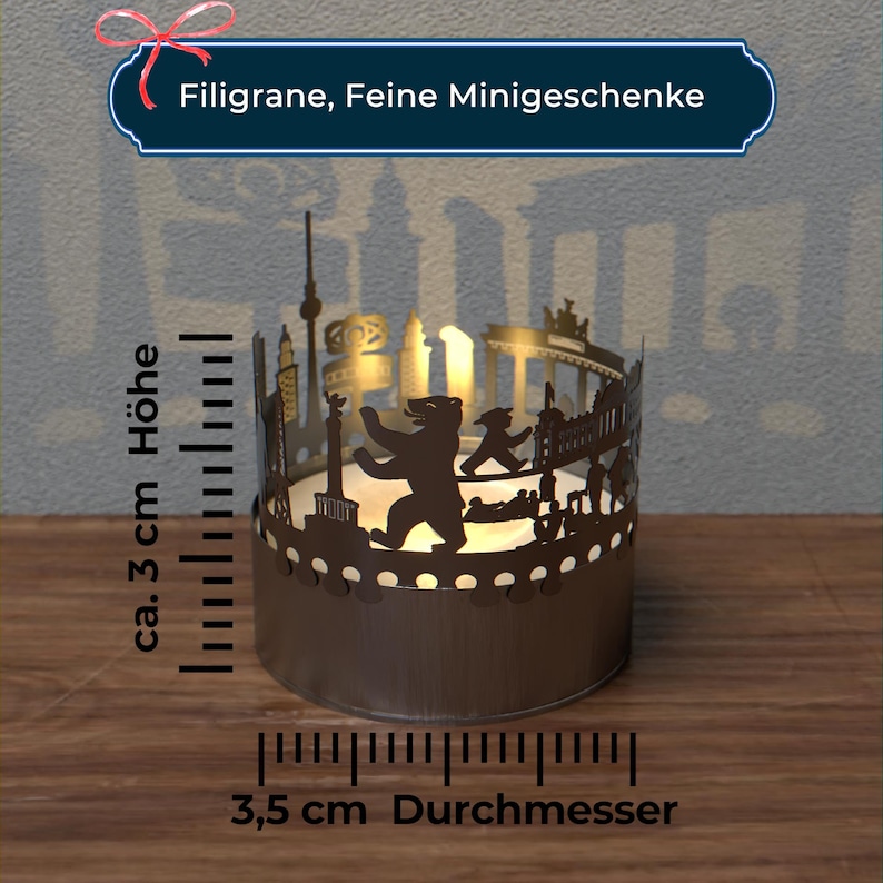 K&ouml;nnte beinhalten: Ein Kerzenhalter aus Metall mit einer Silhouette der Berliner Skyline, einschlie&szlig;lich des Brandenburger Tors, des Reichstagsgeb&auml;udes und des Berliner B&auml;ren. Der Kerzenhalter hat einen Durchmesser von 3,5 cm und eine H&ouml;he von 3 cm.