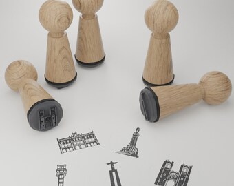 May include: Five wooden stamps with different designs. The stamps are all brown and have a black base. The designs include a building, a tower, a cross, a church, and a statue.