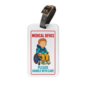 May include: A white rectangular luggage tag with a black leather strap and buckle. The tag features a cartoon illustration of a person in a wheelchair, with the red text MEDICAL DEVICE at the top and the blue text PLEASE HANDLE WITH CARE at the bottom.