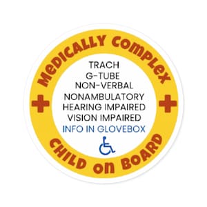 May include: A circular sticker with a yellow border and white center. The text reads MEDICALLY COMPLEX, TRACH, G-TUBE, NON-VERBAL, NONAMBULATORY, HEARING IMPAIRED, VISION IMPAIRED, INFO IN GLOVEBOX, and CHILD ON BOARD, with two red crosses and a blue wheelchair icon.