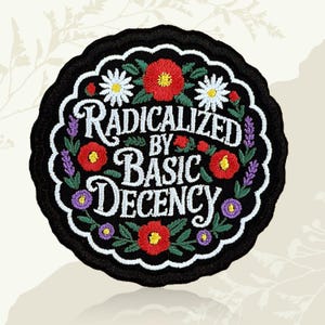 May include: A black, circular embroidered patch with the words "RADICALIZED BY BASIC DECENCY" in white script. The patch is decorated with red poppies, white daisies, and purple lavender and other flowers.