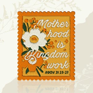 May include: Embroidered patch with the words "Motherhood is Kingdom work" and the Bible verse Proverbs 31:25-27. The patch features a white flower with an orange center, orange berries, and a scalloped orange border.
