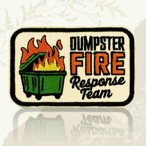 May include: A rectangular embroidered patch with a cream background and a black border. It features a green dumpster engulfed in orange and yellow flames. The text reads DUMPSTER FIRE in bold orange letters and Response Team in black script.