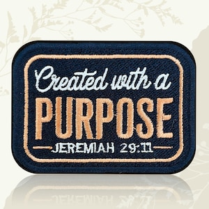 May include: Embroidered patch with the text "Created with a PURPOSE" in white and orange thread on a navy blue background. The patch also includes the Bible verse Jeremiah 29:11.