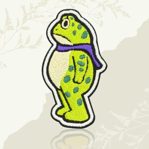 May include: Embroidered patch of a cartoon frog with a purple scarf and green spots on a lime green body. The frog has a white belly and is outlined in black and white. Ideal for customising clothing or accessories.