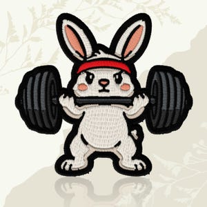 May include: Embroidered patch of a white rabbit lifting a barbell. The rabbit has black outlines, pink inner ears, and a red headband. The barbell has black weights. The patch is set against a light beige background.