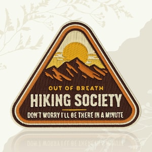 May include: Embroidered patch with a triangular shape, featuring a mountain landscape with a yellow sun. The text "OUT OF BREATH HIKING SOCIETY" and "DON'T WORRY I'LL BE THERE IN A MINUTE" are displayed in white. The patch has brown, orange, and yellow tones.