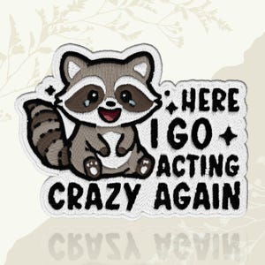 May include: Embroidered patch featuring a cartoon raccoon with a happy expression. The raccoon is gray, brown, and white, with the text "HERE I GO ACTING CRAZY AGAIN" in black. The patch has a white border and is likely for clothing or accessories.