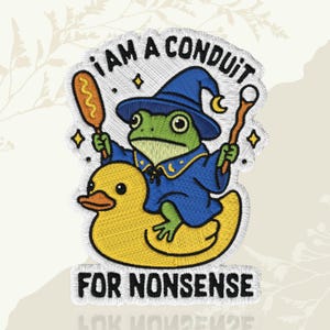 May include: Embroidered patch showing a frog wizard in a blue robe and hat, riding a yellow rubber duck. The frog holds a corn dog and a wand. Text reads "I AM A CONDUIT FOR NONSENSE."