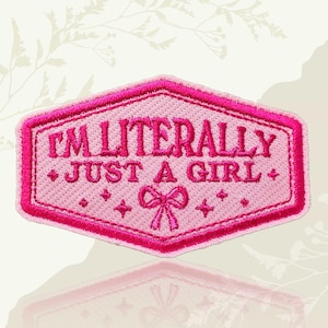 May include: A pink embroidered patch in a hexagonal shape. The patch features the text "I'M LITERALLY JUST A GIRL" in a bold, dark pink font. The design includes small star accents and a bow at the bottom, all on a light pink background.
