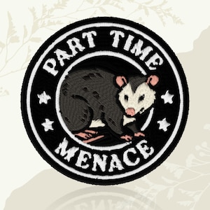 May include: Embroidered patch featuring a black and gray opossum illustration. The patch is circular with the words "PART TIME MENACE" in white lettering. Includes white star accents. A fun, quirky accessory.