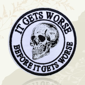 May include: A circular white patch featuring a black skull illustration and text. The text, in black, reads "IT GETS WORSE BEFORE IT GETS WORSE". The skull is centrally positioned with detailed shading.