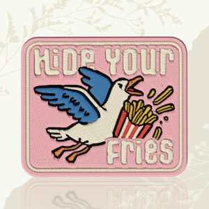 May include: Embroidered patch with a pink background and a white border. The patch features a seagull with blue wings and orange legs, carrying a carton of fries. Text reads "HIDE YOUR FRIES" in white.