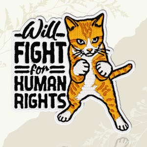May include: An embroidered patch featuring an orange and white tabby cat in a boxing stance with its paws raised. To the left, black embroidered text reads: Will FIGHT for HUMAN RIGHTS. The design has a white border and detailed stitching.