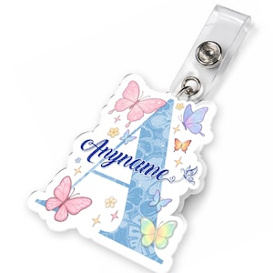May include: A personalized badge reel featuring a large letter "A" in light blue with a floral pattern. The design includes pink, orange, and yellow butterflies, with the name "Anyname" in a script font.