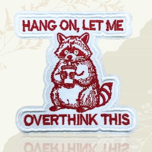 May include: Embroidered patch with a red raccoon holding a coffee cup. The patch reads "HANG ON, LET ME" above the raccoon and "OVERTHINK THIS" below. The patch is white with red embroidery, suitable for clothing or bags.